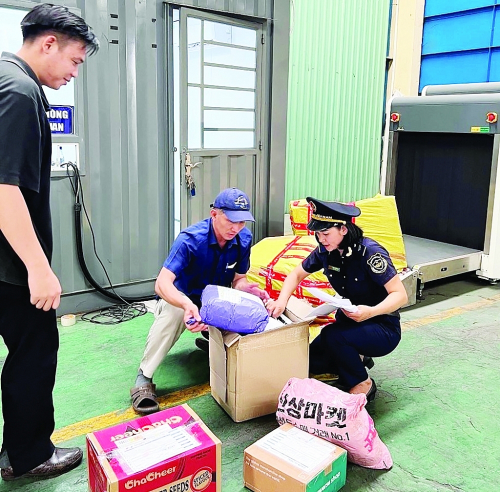 Công chức Chi cục Hải quan Sóng Thần kiểm tra thực tế hàng hóa gửi qua chuyển phát nhanh. 	Ảnh: Thu Mai