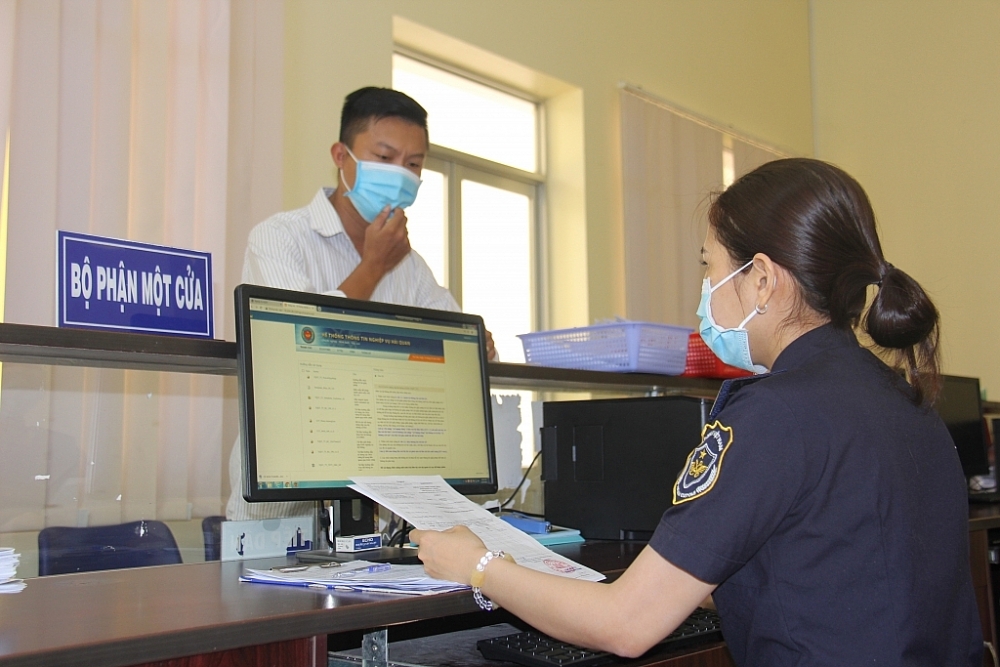 Công chức Chi cục Hải quan cửa khẩu Dinh Bà - Cục Hải quan Đồng Tháp làm thủ tục cho doanh nghiệp .	  	Ảnh: T.H