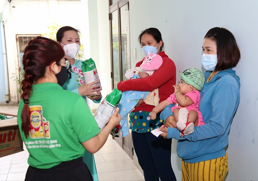 Người dân có hoàn cảnh khó khăn vui mừng bế con đi nhận sữa tại phường 7, quận 8, TPHCM. 
