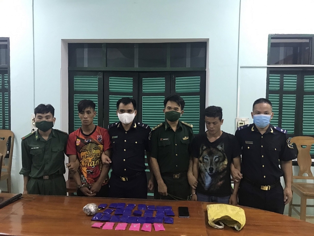 Hai đối tượng (đứng thứ hai từ bên trái và bên phải) cùng tang vật bị lực lượng chức năng bắt giữ. Ảnh: BĐBP