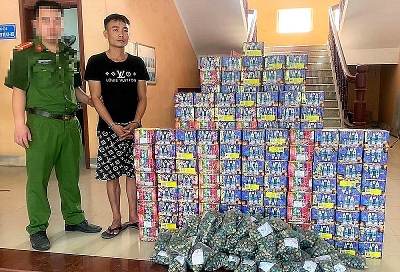 Đối tượng (áo đen) cùng tang vật. Ảnh: CANA