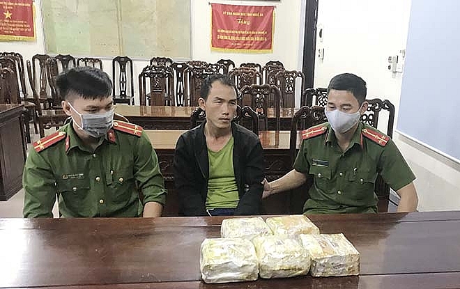 Đối tượng (ngồi giữa) cùng tang vật. Ảnh: CA NA
